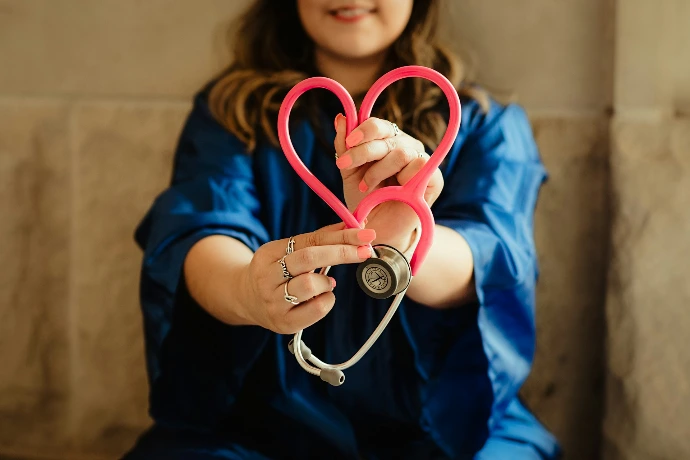 Professionnelle de santé tenant un stéthoscope en forme de cœur illustrant le bien-être et la prévention
