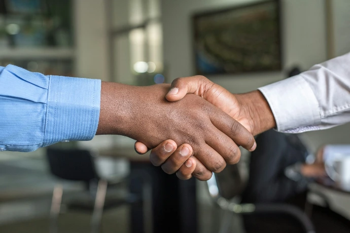 Poignée de main entre deux professionnels symbolisant la mise en relation et l’accès à l’emploi